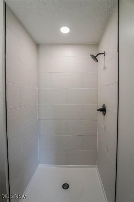 bathroom featuring a textured ceiling and a stall shower