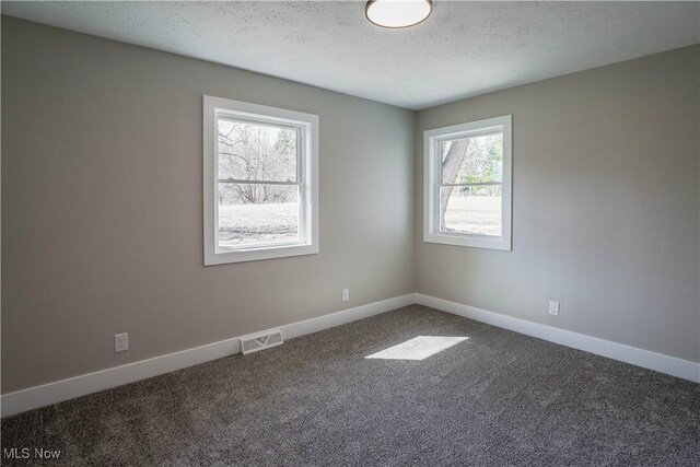 unfurnished room featuring baseboards, visible vents, a textured ceiling, and carpet