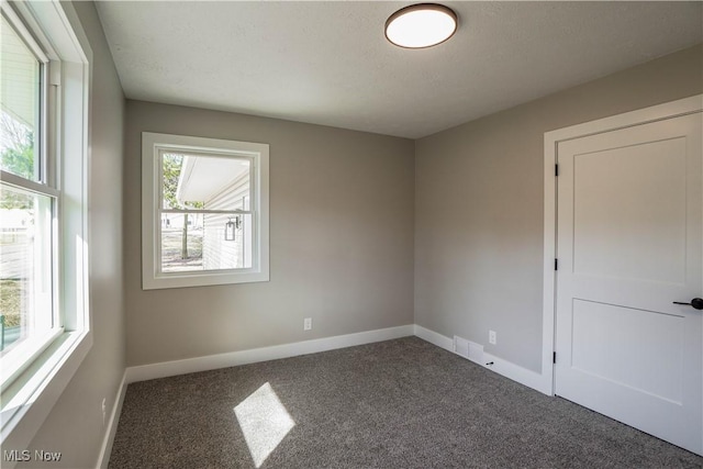 carpeted spare room with visible vents, baseboards, and a healthy amount of sunlight