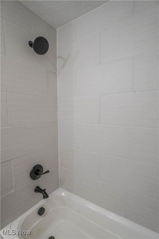 bathroom with bathing tub / shower combination and a textured ceiling