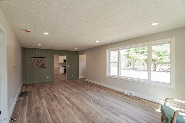 unfurnished living room with recessed lighting, wood finished floors, visible vents, and baseboards