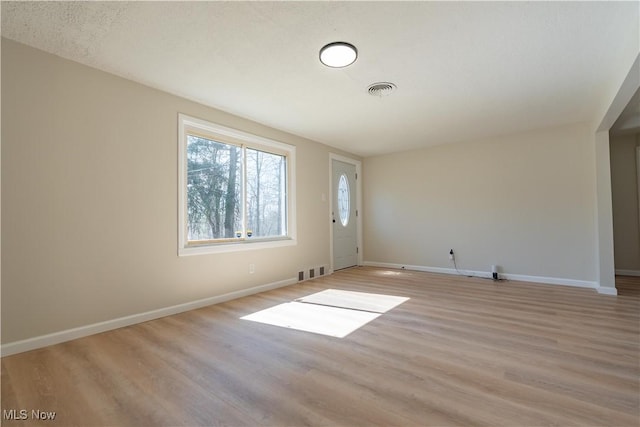 spare room with baseboards, visible vents, and light wood finished floors