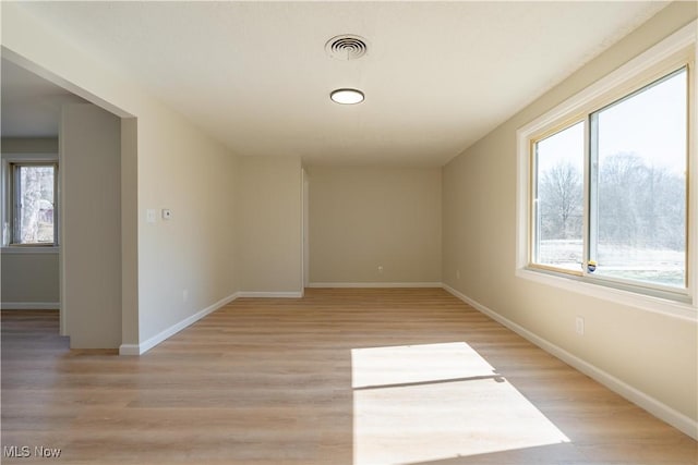 spare room featuring light wood-style flooring, baseboards, and visible vents