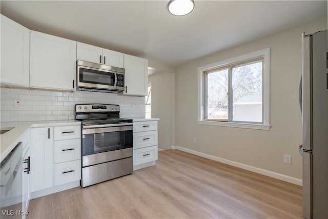 kitchen featuring tasteful backsplash, light countertops, light wood-style floors, white cabinets, and stainless steel appliances