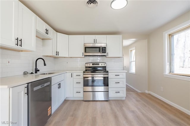 kitchen with visible vents, decorative backsplash, white cabinets, stainless steel appliances, and a sink