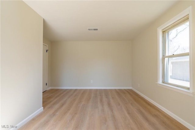 spare room with visible vents, light wood-type flooring, and baseboards