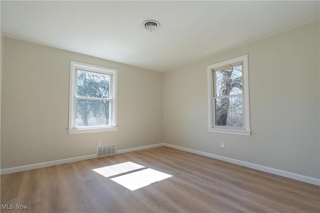 unfurnished room featuring wood finished floors, baseboards, and visible vents