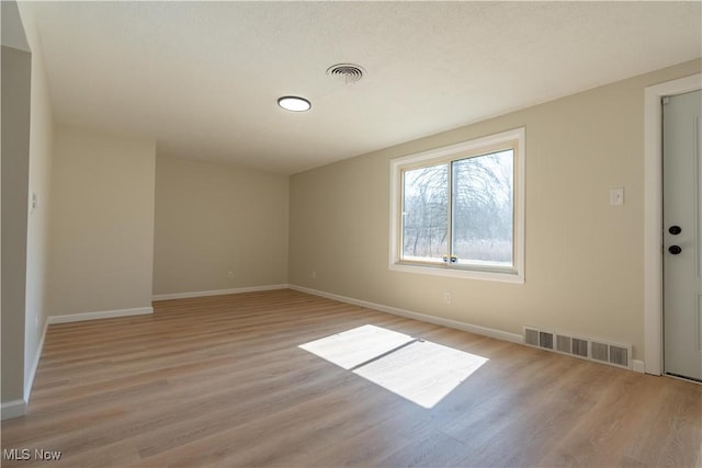 empty room featuring visible vents, baseboards, and light wood-style flooring