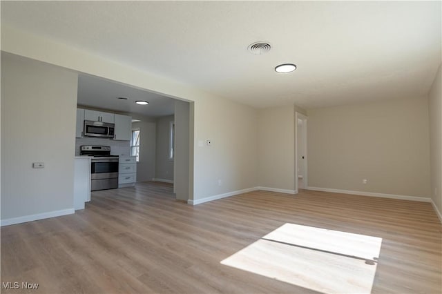 unfurnished living room featuring visible vents, light wood-style flooring, and baseboards