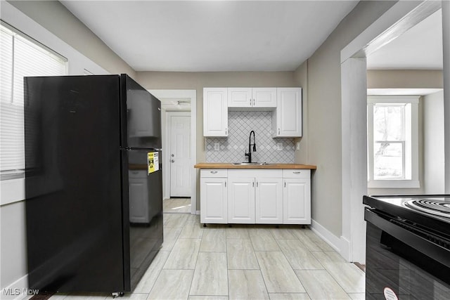 kitchen with a sink, wooden counters, black appliances, and white cabinetry