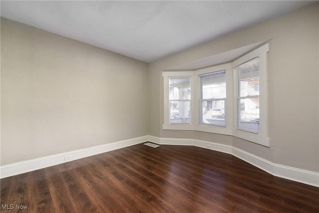 spare room with dark wood finished floors, lofted ceiling, and baseboards