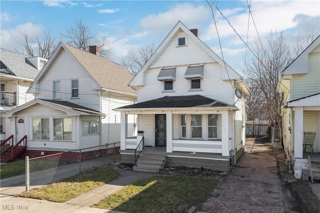 view of front of property with a shingled roof, a porch, fence, and a chimney