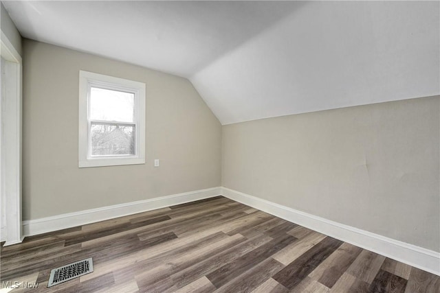 bonus room with baseboards, lofted ceiling, and dark wood finished floors