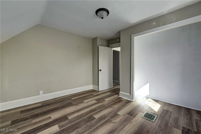 unfurnished bedroom with visible vents, baseboards, lofted ceiling, and wood finished floors