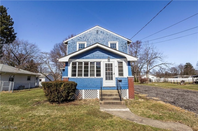 view of front facade featuring entry steps, a front lawn, and fence