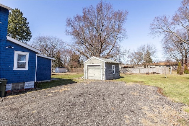 view of yard with a garage, an outdoor structure, dirt driveway, and fence