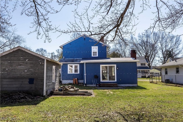 rear view of house featuring entry steps, a lawn, and a chimney