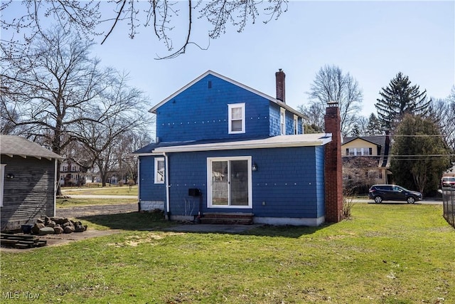 back of property featuring entry steps, a chimney, and a yard