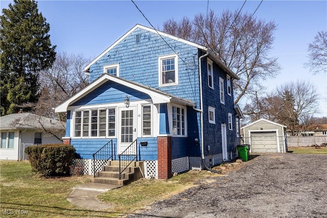 view of front facade featuring an outbuilding, a front yard, driveway, entry steps, and a detached garage