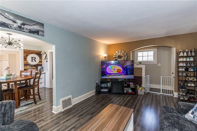 living area with visible vents, baseboards, wood finished floors, arched walkways, and a notable chandelier