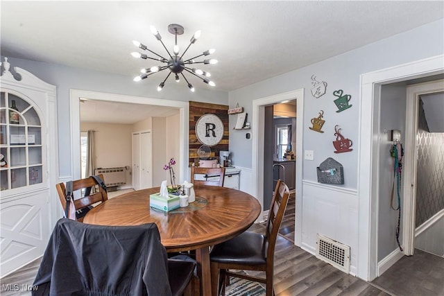 dining room with visible vents, radiator, dark wood finished floors, a wainscoted wall, and a notable chandelier