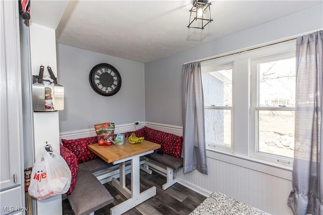 dining area featuring dark wood-style flooring and wainscoting