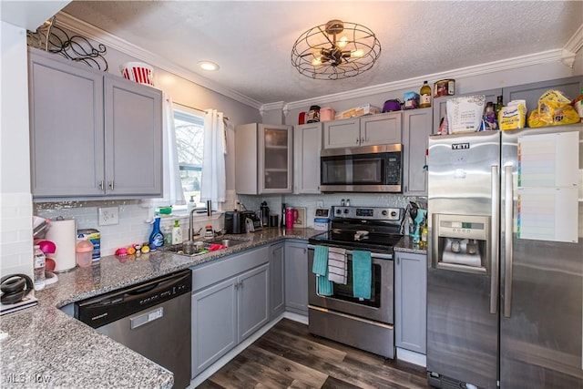 kitchen with ornamental molding, gray cabinets, appliances with stainless steel finishes, and a sink