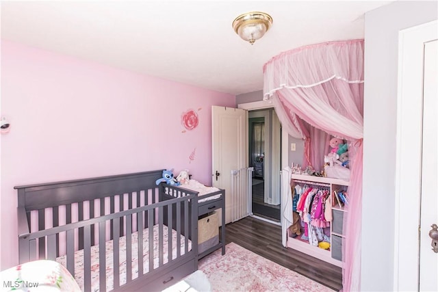 bedroom with a crib and wood finished floors