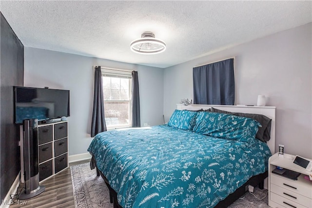 bedroom featuring wood finished floors, baseboards, and a textured ceiling