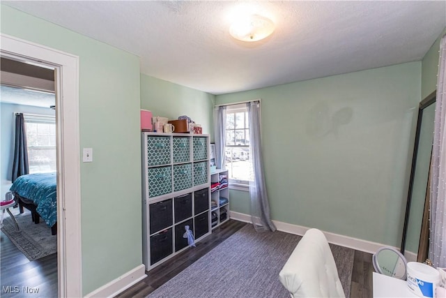 bedroom featuring a textured ceiling, baseboards, and wood finished floors