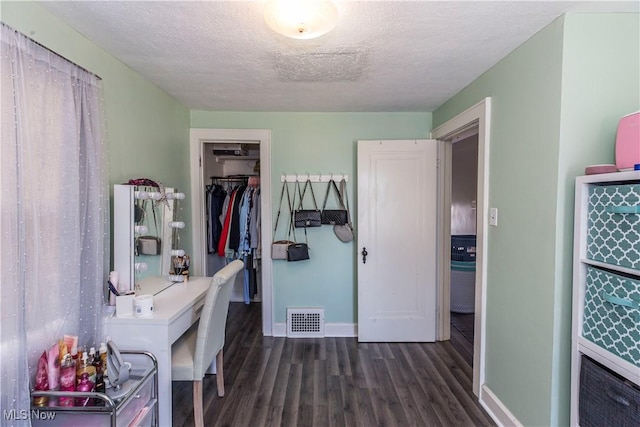 bedroom with visible vents, a walk in closet, baseboards, a textured ceiling, and dark wood-style flooring