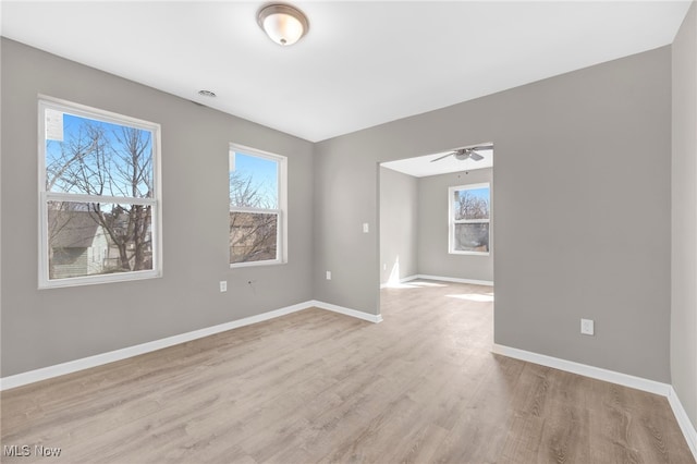 unfurnished room with a wealth of natural light, baseboards, and light wood-style floors