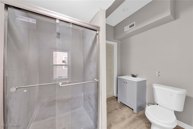 bathroom featuring a shower stall, toilet, wood finished floors, and visible vents