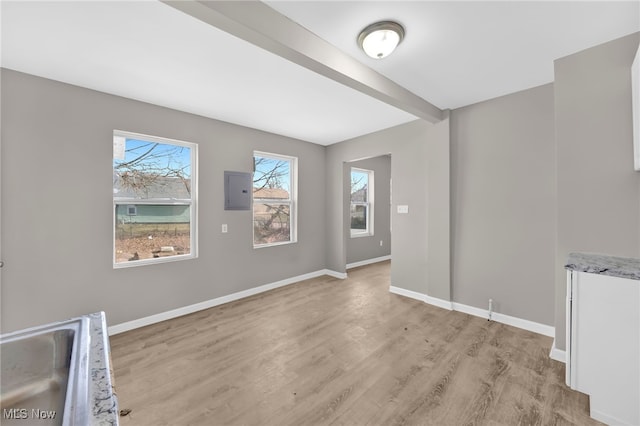 spare room with beamed ceiling, light wood-style flooring, and baseboards