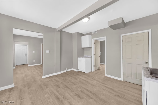 unfurnished living room featuring visible vents, baseboards, and light wood finished floors