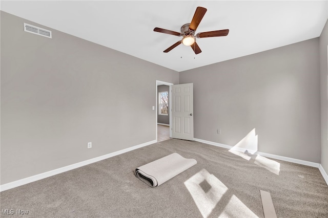 carpeted spare room featuring visible vents, baseboards, and a ceiling fan