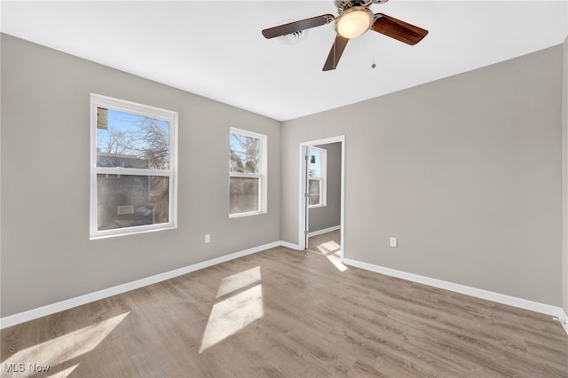 empty room featuring a ceiling fan, baseboards, and wood finished floors