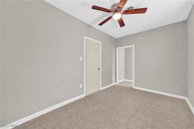 empty room with carpet, a ceiling fan, and baseboards