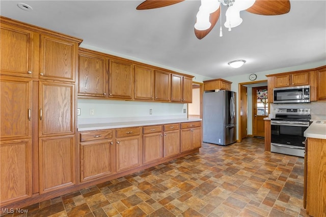 kitchen with brown cabinets, appliances with stainless steel finishes, a ceiling fan, and light countertops