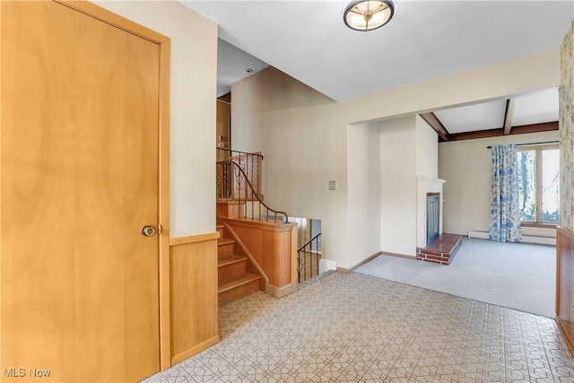 interior space featuring stairway, beamed ceiling, baseboards, a baseboard heating unit, and a brick fireplace