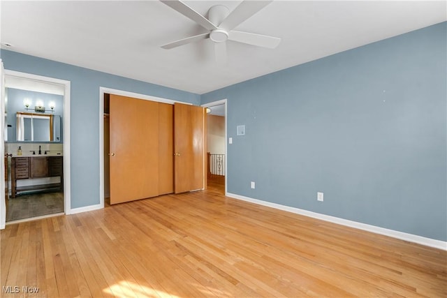 unfurnished bedroom featuring a closet, baseboards, light wood finished floors, and a sink