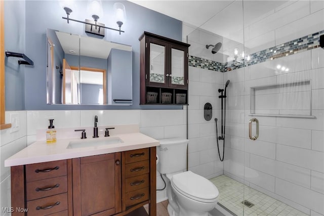 full bathroom with tile walls, a shower stall, toilet, and vanity