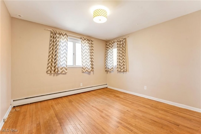 unfurnished room featuring a baseboard heating unit, baseboards, and hardwood / wood-style floors