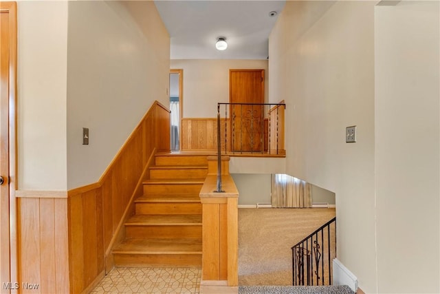 stairs featuring a wainscoted wall and wooden walls