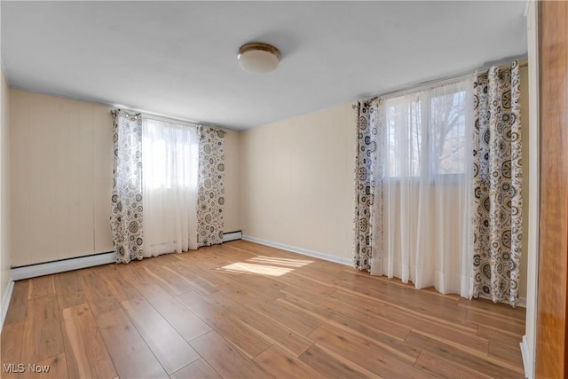 unfurnished room featuring baseboard heating, a baseboard heating unit, baseboards, and hardwood / wood-style floors