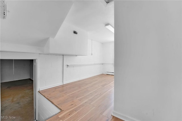 interior space with a baseboard heating unit and wood finished floors