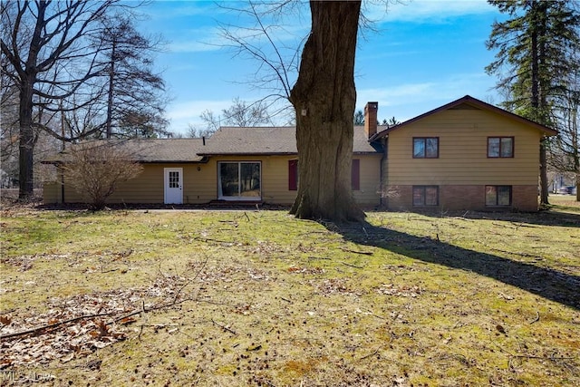 back of house featuring a chimney and a yard