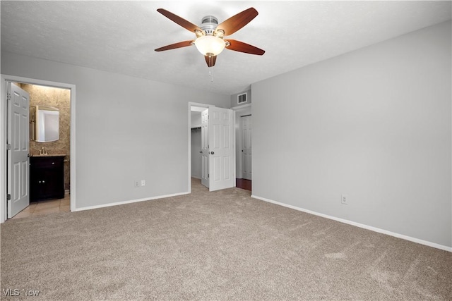 unfurnished bedroom featuring visible vents, light carpet, a walk in closet, connected bathroom, and baseboards