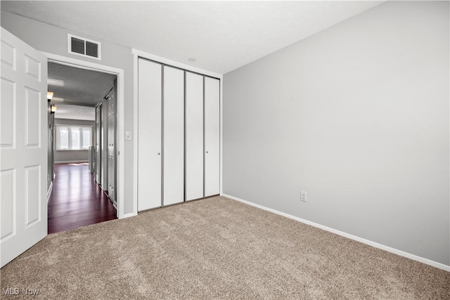 unfurnished bedroom with baseboards, visible vents, carpet floors, and a closet