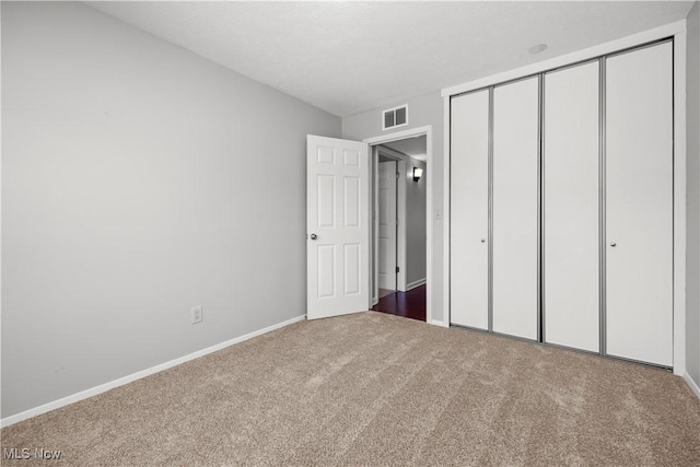 unfurnished bedroom featuring carpet, visible vents, a closet, and baseboards